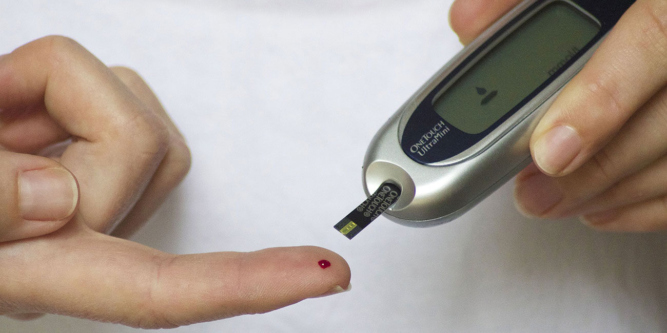 Finger mit Bluttropfen und Diabetes Blutzuckermessgerät